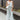 Full body front view of model wearing the Sea Breeze Pants that have white and sage sheer fabric with a marbled pattern, flared legs with a ruffle tier hem, and a  side zipper.