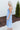 Side view of model wearing the Living In A Fairytale Midi Dress that has periwinkle organza pleated fabric, periwinkle lining, midi length, a square neck, and adjustable straps.