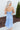 Back view of model wearing the Living In A Fairytale Midi Dress that has periwinkle organza pleated fabric, periwinkle lining, midi length, a square neck, and adjustable straps.