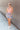 Full body front view of model wearing the Loves Me Not Floral Skort that has a floral pattern, a ruffle tiered skirt, a smocked waistband, and white shorts lining.