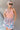 Front view of model wearing the Loves Me Not Floral Skort that has a floral pattern, a ruffle tiered skirt, a smocked waistband, and white shorts lining.