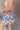 Close side view of model wearing the Loves Me Not Floral Skort that has a floral pattern, a ruffle tiered skirt, a smocked waistband, and white shorts lining.