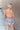 Back view of model wearing the Loves Me Not Floral Skort that has a floral pattern, a ruffle tiered skirt, a smocked waistband, and white shorts lining.