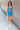 Full body front view of model wearing the Get Ready Dress that has stretchy turquoise fabric, mini length, a round neckline, spaghetti straps.
