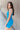 Side view of model wearing the Get Ready Dress that has stretchy turquoise fabric, mini length, a round neckline, spaghetti straps.