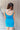 Back view of model wearing the Get Ready Dress that has stretchy turquoise fabric, mini length, a round neckline, spaghetti straps.