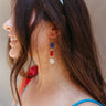 Side view of model wearing the Let Freedom Ring Earrings which features three gold circle dangle with red, white and blue beads.