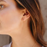 Side view of model wearing the All My Love Dangle Earring which features rhinestones linked to another rhinestone with a gold chain.