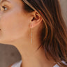 Side view of model wearing the Make You Happier Earring which features gold dangle links with two rectangle shaped rhinestones.