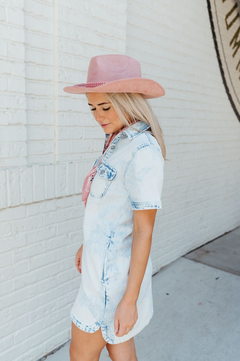 Side view of model wearing the Keep Adventuring Hat that features a cowboy-shaped body, mauve suede fabric, and a light pink braided band detail with a tie.