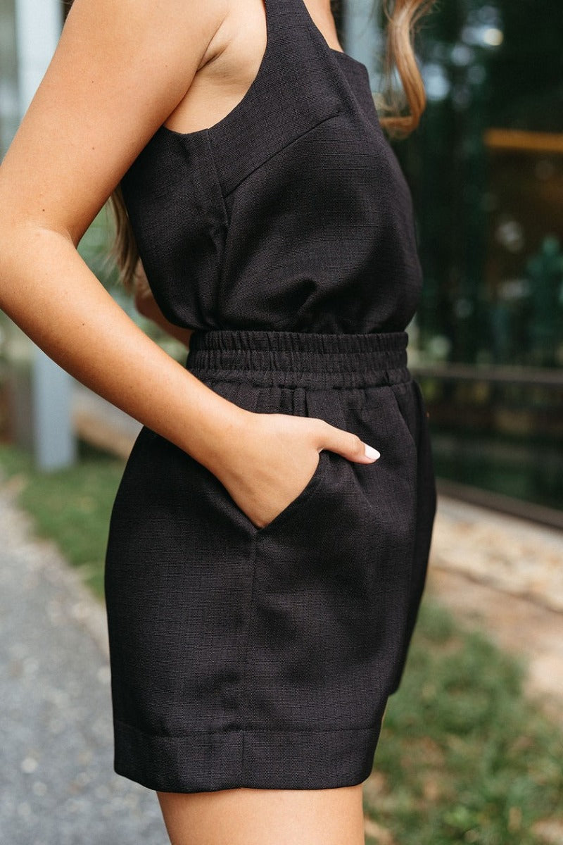 Close side view of model wearing the Love You More Shorts that have textured black fabric, front pockets, and an elastic waistband