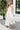 Front view of model wearing the Summer Romance Maxi Dress that has white fabric, maxi length, white lining, a ruffled hem, a plunge neckline, layered upper details, ruffle straps, and back corset ties