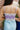 Close up back view of model wearing the Catching Feelings Midi Dress which features turquoise and purple color-blocked satin fabric, midi length, white lace details, adjustable straps, and a monochromatic side zipper with a hook closure.
