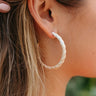 Side view of model wearing the Road Trip Hoop Earrings in Ivory that feature large, open hoops wrapped in ivory paper.
