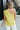 Back view of model wearing the On My Own Top which features chartreuse fabric, monochromatic lining, and one-shoulder with ruched tie details.