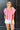 Front view of model wearing the All About Me Top which features pink gauze fabric, a square neckline, short flare sleeves, and an open back with a tie closure.