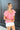 Side view of model wearing the All About Me Top which features pink gauze fabric, a square neckline, short flare sleeves, and an open back with a tie closure.