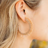 Close side view of model wearing the Santa Cruz Hoop Earrings in Light Brown that have large, open hoop with light brown fringe design with gold and light brown beads