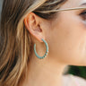 Side view of model wearing the Keep It Going Earring in Sage which features medium, open gold bubble hoops wrapped in sage fabric.