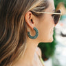 Side view of model wearing the Let It Shine Earring in Sage which features open, medium hoops wrapped in sage fabric with monochromatic beads.