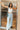 Full body front view of model wearing the Live Fast Cargo Pants that have light blue denim like fabric, two front pockets, an elastic waistband, and wide legs.