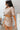 Side view of model wearing the Next Level Skirt that has taupe fabric, mini length, a monochromatic side button-up design, and a side zipper with a hook closure