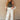 Front view of model wearing the Keep It Going Cargo Pants that have white denim fabric, cargo pockets, front pockets, a zipper with a button closure, belt loops, two back pockets and green stitch details.