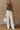 Front view of model wearing the Keep It Going Cargo Pants that have white denim fabric, cargo pockets, front pockets, a zipper with a button closure, belt loops, two back pockets and green stitch details.