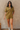 Front view of model wearing the Western Winds Romper that has olive gauze fabric, pearlescent buttons, a collared neckline, two front pockets, and short cuffed sleeves.