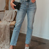 Front view of model wearing the Ceros: Aurora Embellished Jeans that have light blue denim wash fabric, rhinestone details, front zippe, belt loops, pockets, brown stitching, and straight legs.