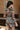 Back view of model wearing the Donna Floral Romper which features black mesh fabric with a rust, mustard, blue, sage and white floral pattern, black lining, lettuce hem, a v-neckline with a tie closure, long sleeves, and a back key hole with a button clos