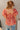Back view of model wearing the New Life Floral Top which features light pink fabric with a rust floral pattern, a peplum body, a square neckline, short puff sleeves and a smocked back.