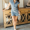 Full body front view of model wearing the Dallas Belted Zip-Front Denim Romper that has blue denim, pockets, a front zipper, a collar, an adjustable belt with a western silver buckle, and short cap sleeves