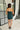 Full body back view of model wearing the Party Time Ruched Teal Strapless Mini Dress that has textured teal fabric, mini length, side ruching, a strapless neck and a back zipper with a hook closure