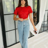 Full body front view of model wearing the Lennox Red Sequin Crop Top that has red sequin fabric, a cropped waist with an angled hem, a round neckline, short sleeves, and a silver back zipper closure.