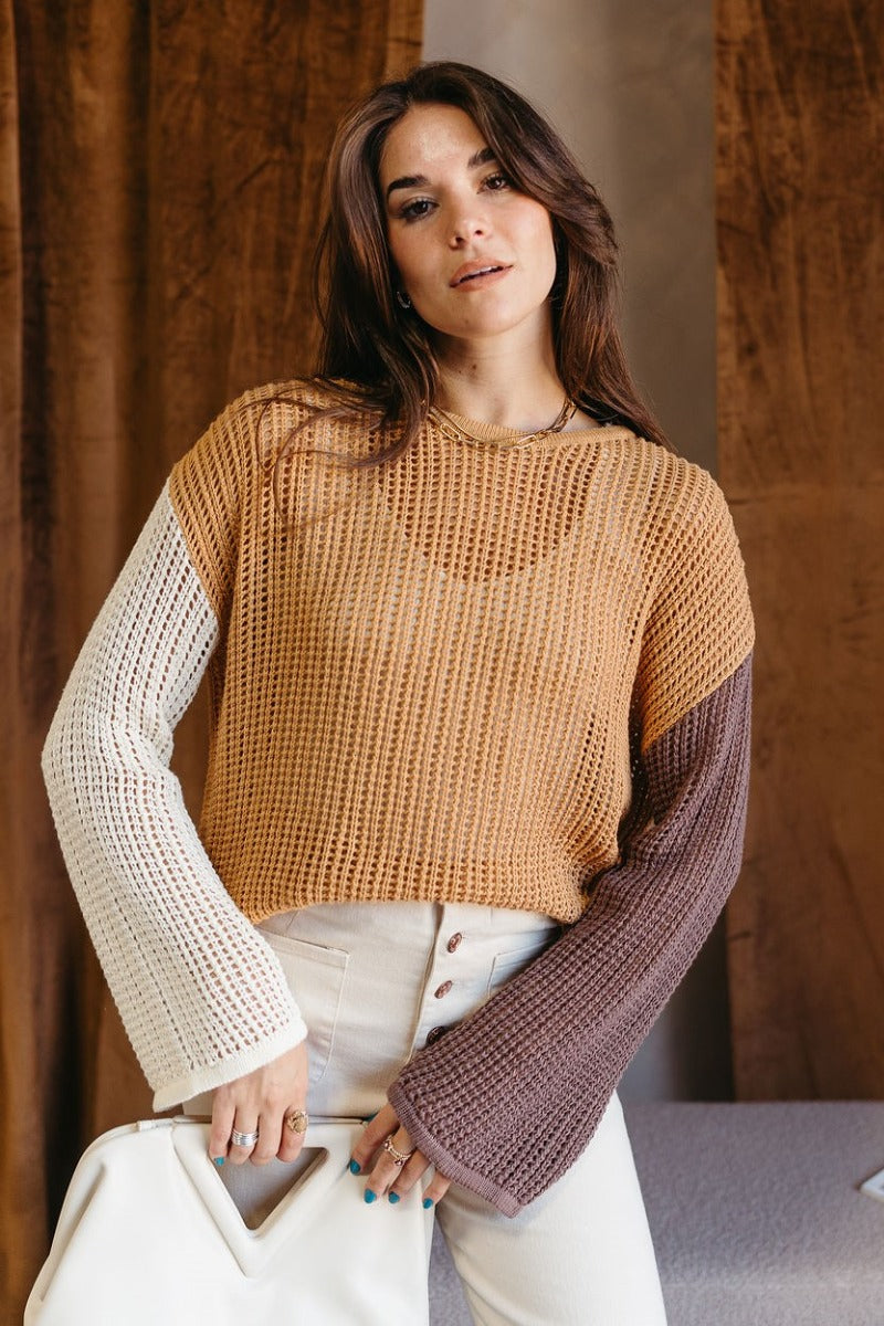 Front view of model wearing the Lucy Camel Colorblock Open Knit Sweater that has brown, cream, and camel open knit fabric with a color-block pattern, a round neckline, dropped shoulders, and long sleeves.