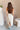 Full body back view of model wearing the Alina Cream Parachute Cargo Midi Skirt that has cream lightweight fabric, midi length, a back slit, two side pockets, an elastic drawstring waistband, and a drawstring hem.