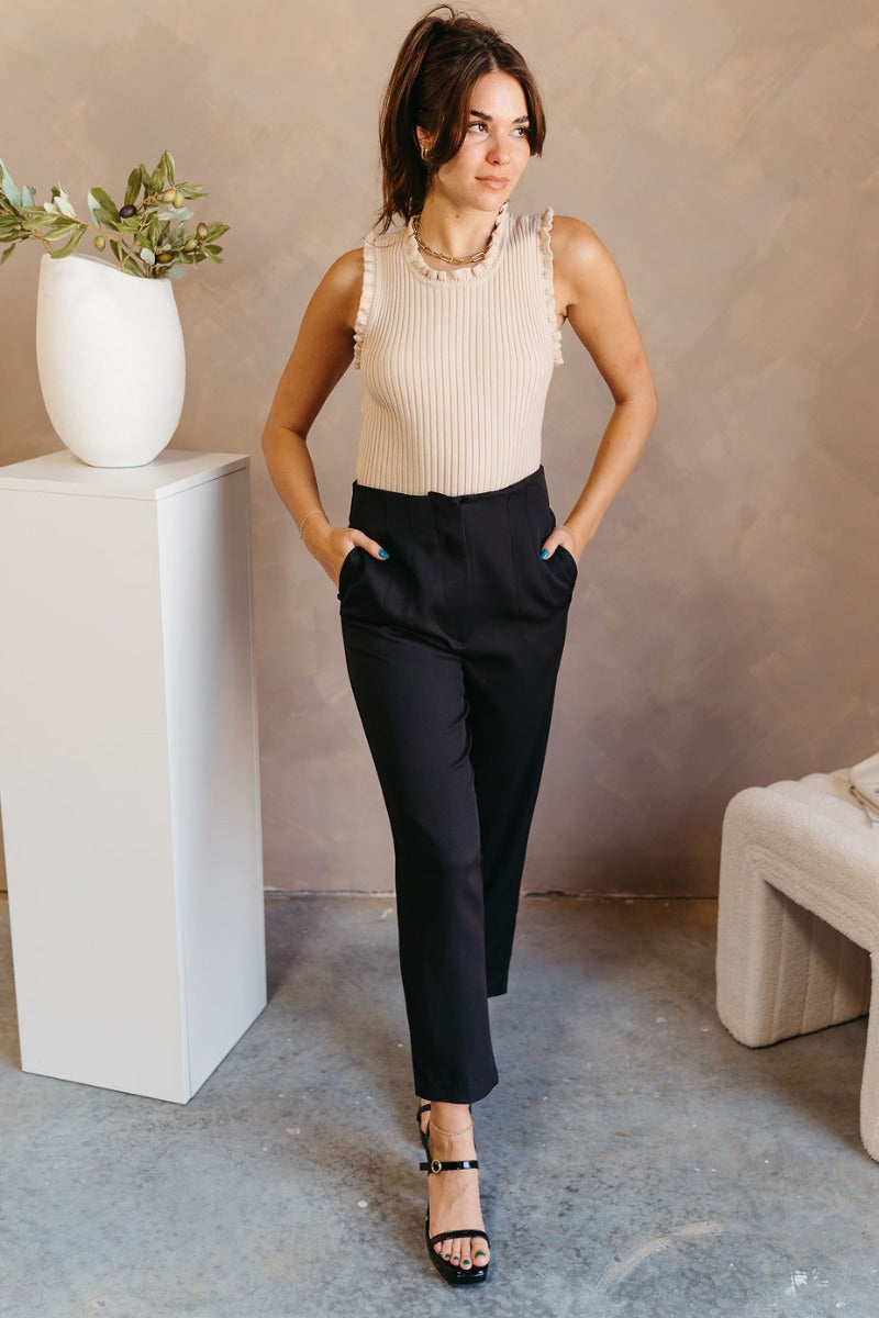 Full body view of model wearing the Tessa Black Dress Pants which features black lightweight fabric, two front pockets, a front zipper with a hook closure, and tapered legs.