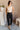 Full body view of model wearing the Tessa Black Dress Pants which features black lightweight fabric, two front pockets, a front zipper with a hook closure, and tapered legs.