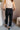 Vack view of model wearing the Tessa Black Dress Pants which features black lightweight fabric, two front pockets, a front zipper with a hook closure, and tapered legs.
