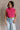 Front view of model wearing the Kelly Pink Cropped Turtleneck Sweater which features hot pink cable knit fabric, a cropped waist, a turtleneck neckline, and a sleeveless design.