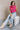 Front view of model wearing the Kelly Pink Cropped Turtleneck Sweater which features hot pink cable knit fabric, a cropped waist, a turtleneck neckline, and a sleeveless design.