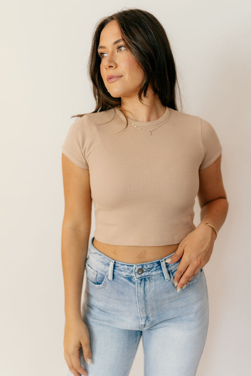Front view of model wearing the Taryn Taupe Basic Short Sleeve Top which features taupe textured cotton fabric, a cropped waist, a round neckline and short sleeves.
