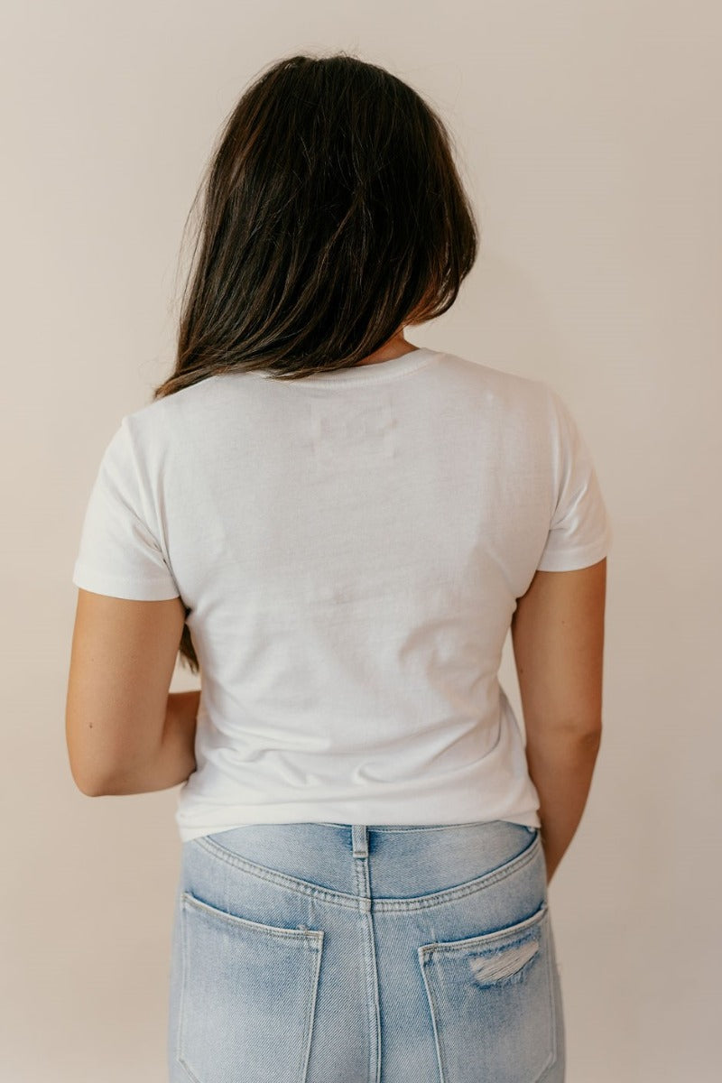 Back view of model wearing the Hannah Off White Short Sleeve Pocket Tee that has off white cotton fabric, a front left chest pocket, a round neckline and short sleeves.