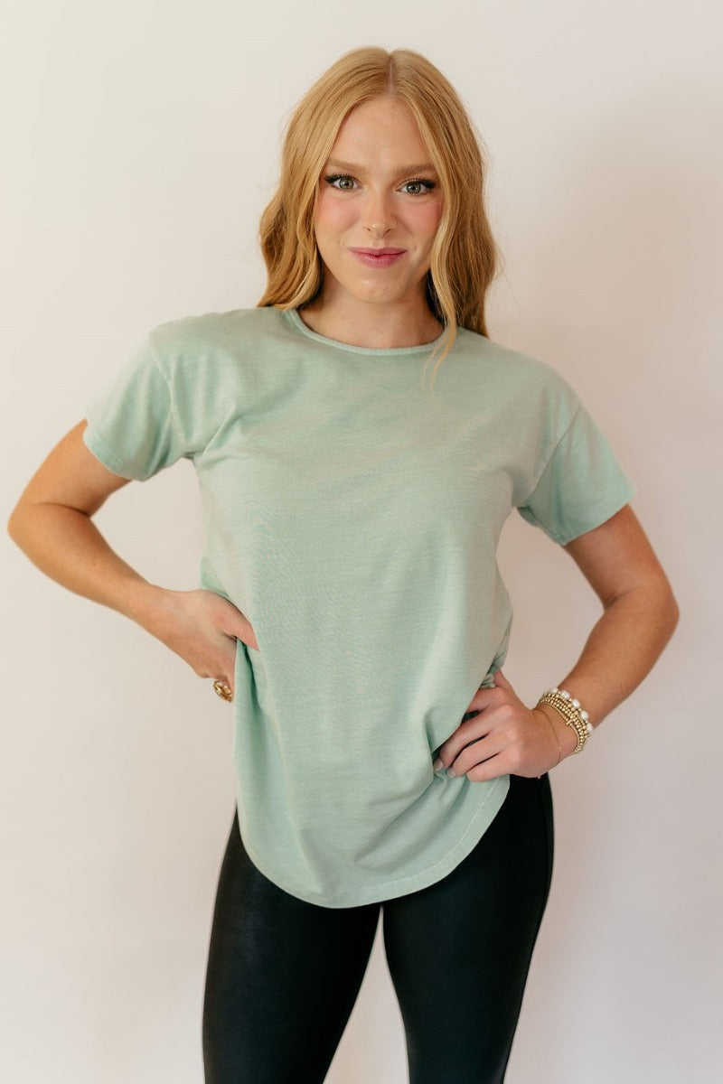 Front view of model wearing the Lillie Mint Green Basic Short Sleeve Top that has mint green knit fabric, a scooped hem, a round neckline and short sleeves.