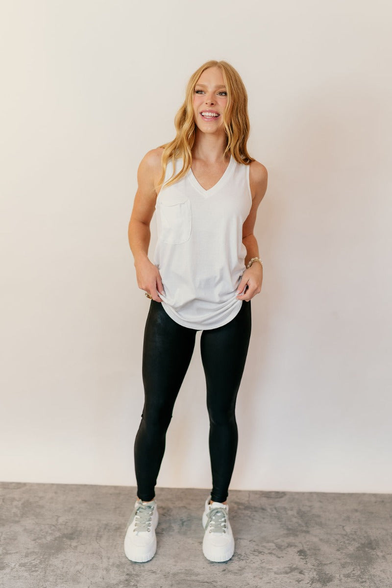 Full body front view of model wearing the Hadley Off White V-Neck Pocket Tank that has off white knit fabric, a scooped hem, a front right chest pocket with raw hems, a v-neck and a sleeveless racerback design.