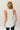Back view of model wearing the Hadley Off White V-Neck Pocket Tank that has off white knit fabric, a scooped hem, a front right chest pocket with raw hems, a v-neck and a sleeveless racerback design.