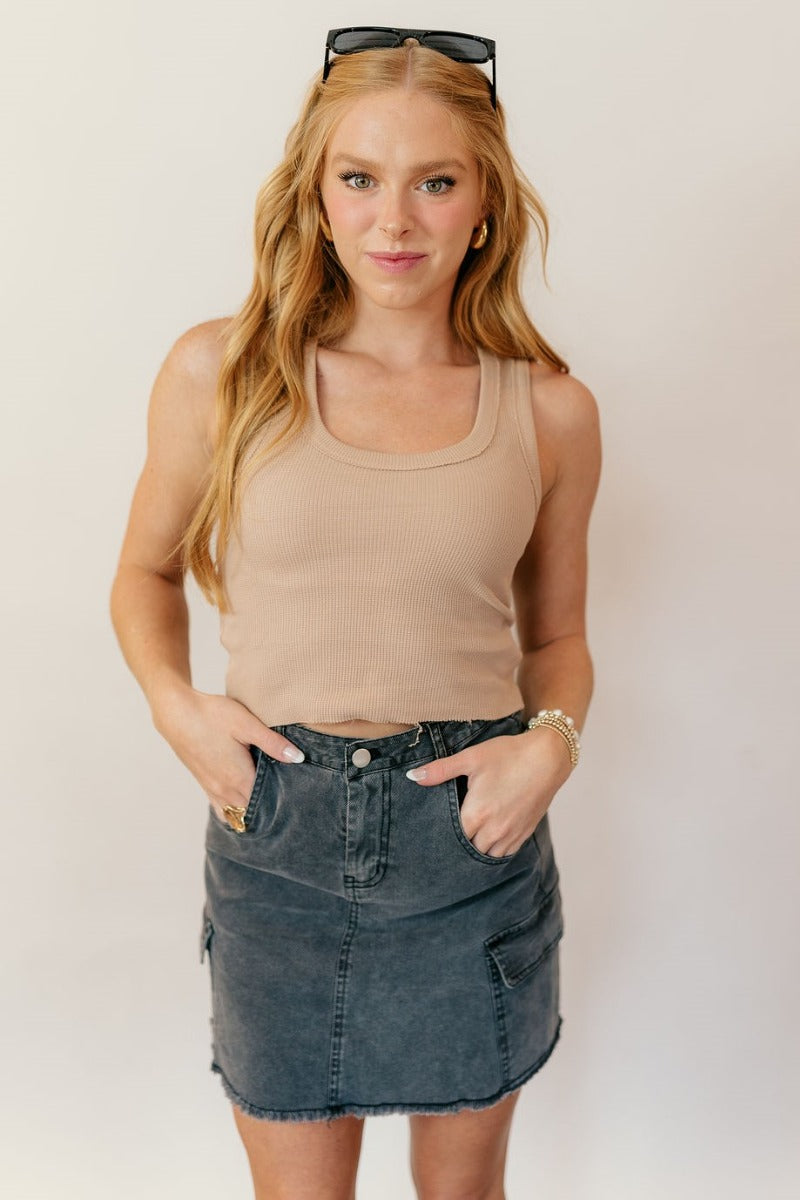 Front view of model wearing the Stella Taupe Raw-Hem Cropped Tank that has taupe textured cotton fabric, a cropped waist, raw hem details, a scooped neckline and a sleeveless design.