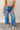 front view of model wearing the Ceros: Billie Wide Leg Paper Bag Jeans that have medium wash denim fabric, pockets, a front zipper, belt loops, an elastic paperbag waist, and wide legs with raw hems.