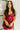 Front view of model wearing the Sasha Burgundy Sequin Strappy Romper that has dark red knit fabric with monochromatic sequins, a v-neckline, adjustable straps, an open back, and a back zipper.